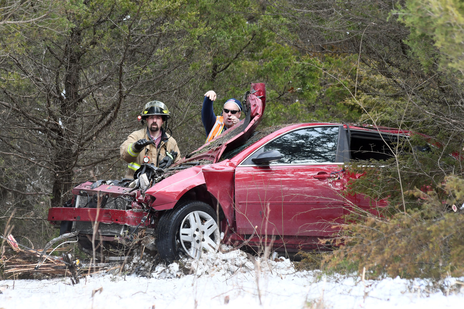 Owensville Fire Chief Jeff Arnold on Monday afternoon directs Triple L Towing’s Faron Limberg to pull the car “up and over” a tree stump during the extrication from a cedar grove along Route P.